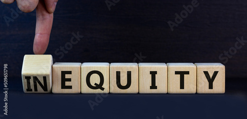 Inequity or equity symbol. Turned wooden cubes and changed the concept word Inequity to Equity. Beautiful grey table grey background. Business and inequity or equity concept. Copy space.