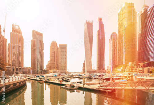 Photography View of high-rise buildings of residential district in Dubai Marina and yachts moored near pier in sunny day
