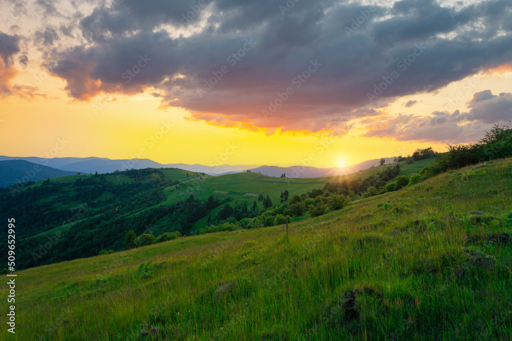 Stunning sunset sky with clouds over green hills. Summer countryside view. Carpathian mountains. Ukraine.