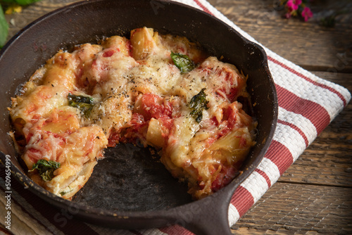 Top view of stuffed rigatoni in cast iron skillet on natural wood table top.