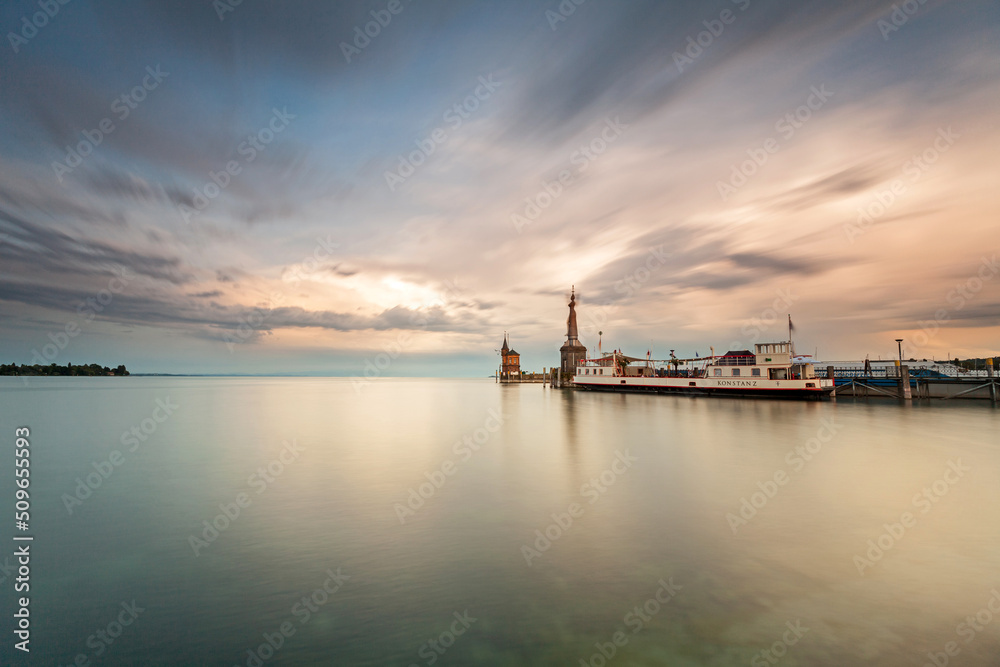 Constance, Germany - Old lighthouse and big statue of Imperia in harbor of Konstanz. Imperia is a landmark of the city. Panoramic view of Constance Lake (Bodensee) in summer.