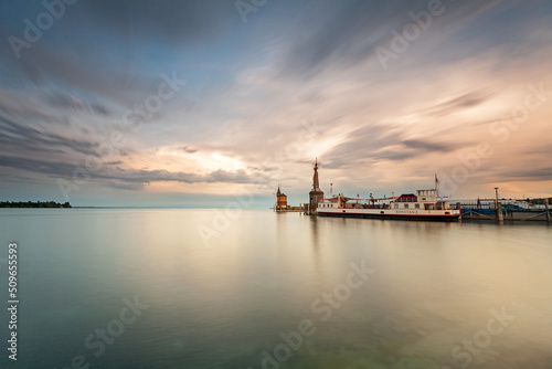 Constance, Germany - Old lighthouse and big statue of Imperia in harbor of Konstanz. Imperia is a landmark of the city. Panoramic view of Constance Lake (Bodensee) in summer.