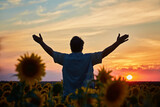 Silhouette of happy successful corn farmer in cornfield in sunset with arms raised in the air