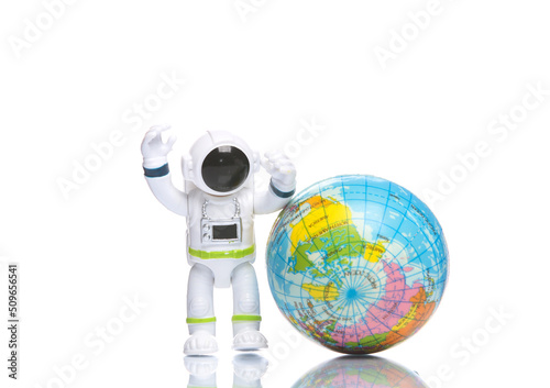 Toy astronaut with globe on white background with reflection