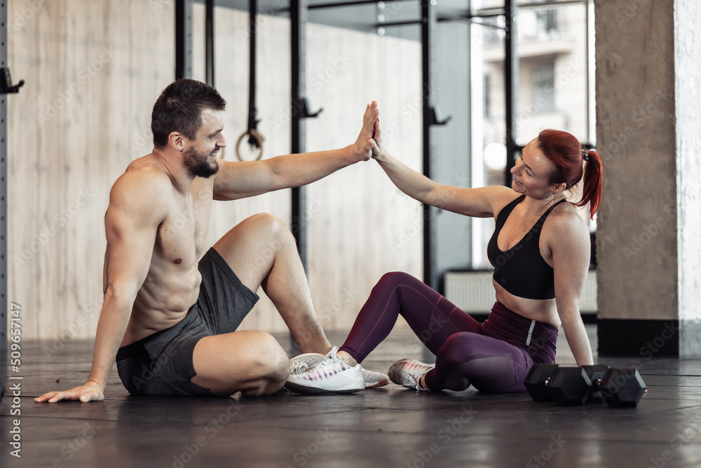 Obraz premium Athletic couple give five in the gym. Healthy lifestyle. Bodybuilding and fitness