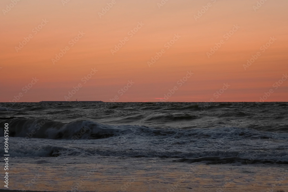Picturesque view of waves of sea in motion of running against sunset sky. Underexposed video clip of oceans waves rolling towards the beach after a vibrant sunset.