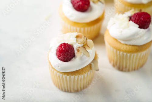 Close-up. Appetizing muffins with cream, raspberries and almonds. Isolated on white background. Confectionery, restaurant, hotel, culinary blog. Advertising, banner, birthday invitation.