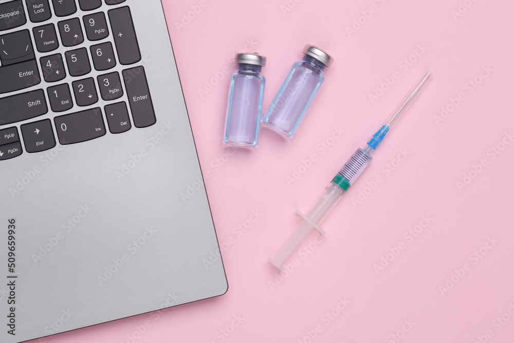 Laptop with a bottle of vacuina and a syringe on pink background. Top view Laptop with a bottle of vacuina and a syringe on pink background. Top view