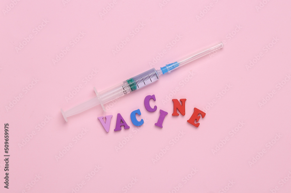 Medicine concept. Syringe with the word vaccine on a pink background Medicine concept. Syringe with the word vaccine on a pink background