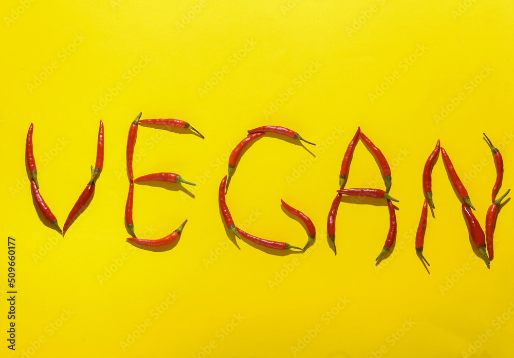Word vegan made from red chili peppers on yellow background Word vegan made from red chili peppers on yellow background