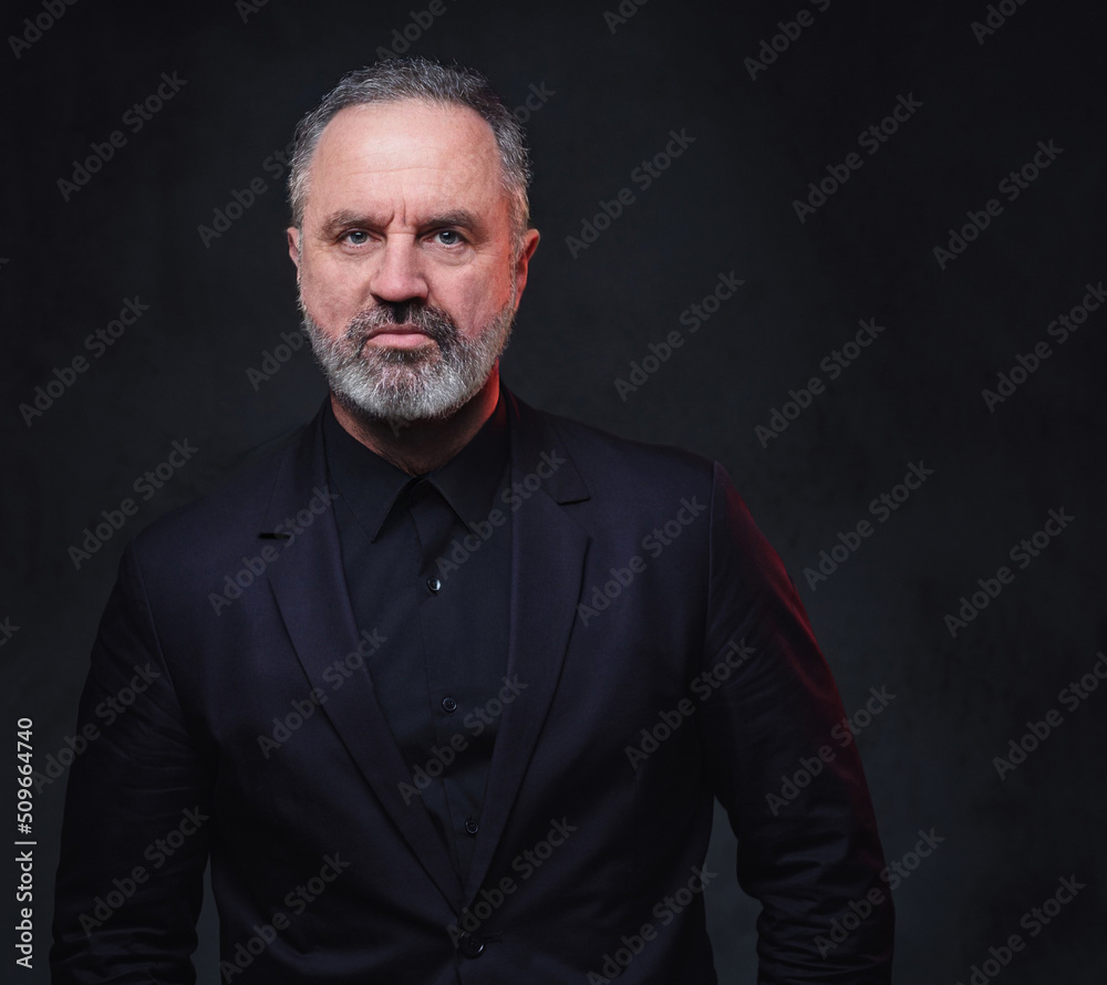 Obraz premium Portrait of handsome elderly dressed in black formal clothes with stylish hairstyle against dark background.
