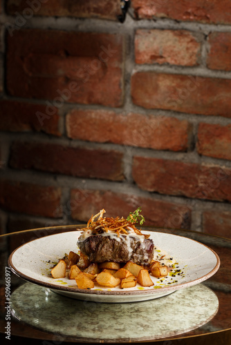 Obraz na płótnie Grilled steak with baked golden potatoes served with crispy onion on top on a brick background. Delicious Recipe. w salonie