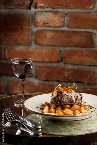 Obraz na płótnie Grilled steak with baked golden potatoes served with crispy onion on top on a brick background. Delicious Recipe. w salonie