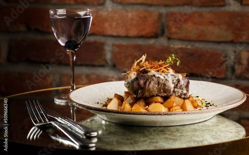 Obraz na płótnie Grilled steak with baked golden potatoes served with crispy onion on top on a brick background. Delicious Recipe. w salonie