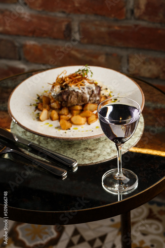 Grilled steak with baked golden potatoes served with crispy onion on top on a brick background. Delicious Recipe.