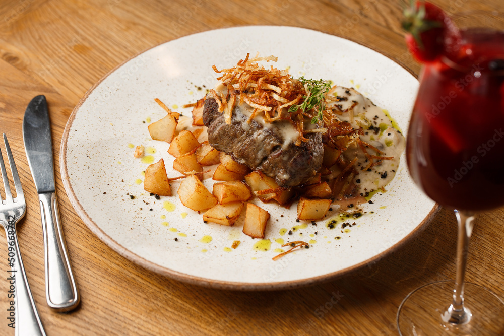 Grilled steak with baked golden potatoes served with crispy onion on top on a brick background. Delicious Recipe.