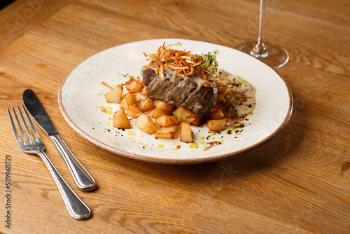 Obraz na płótnie Grilled steak with baked golden potatoes served with crispy onion on top on a brick background. Delicious Recipe. w salonie