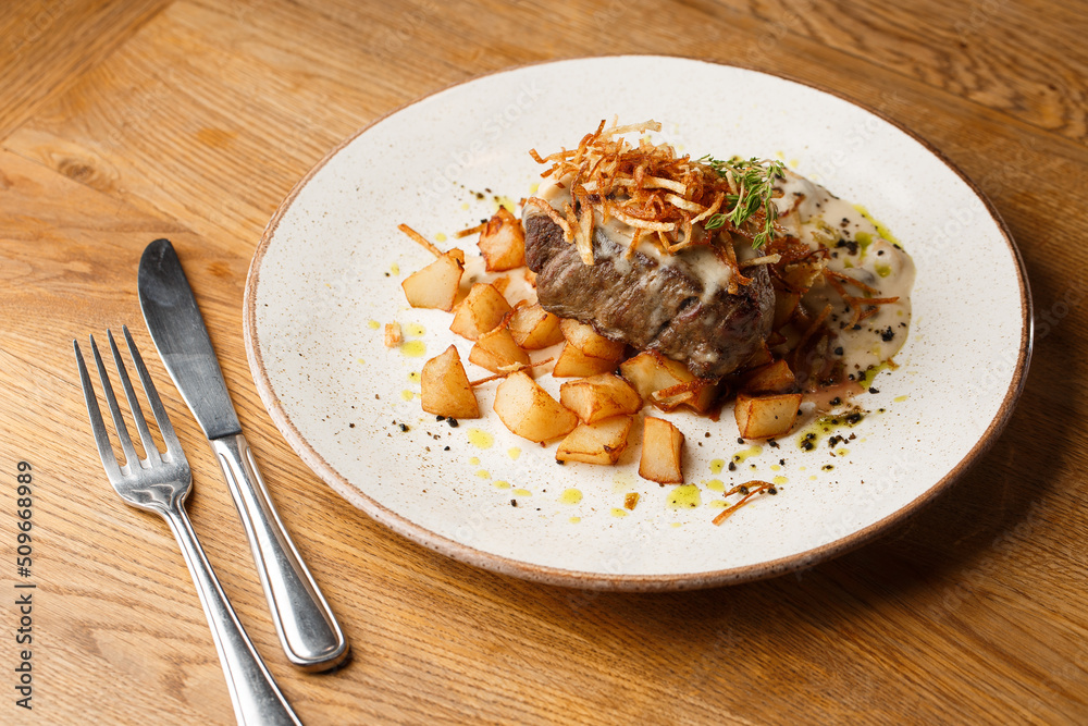 Grilled steak with baked golden potatoes served with crispy onion on top on a brick background. Delicious Recipe.
