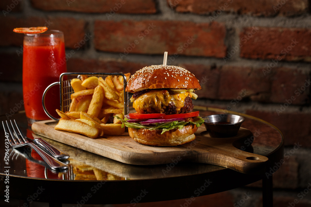 Big cheeseburger with french fries isolated on white background. Hamburger with beef patty onion, tomato, lettuce pickles, melted cheddar, mustards, tomato jam, mayo