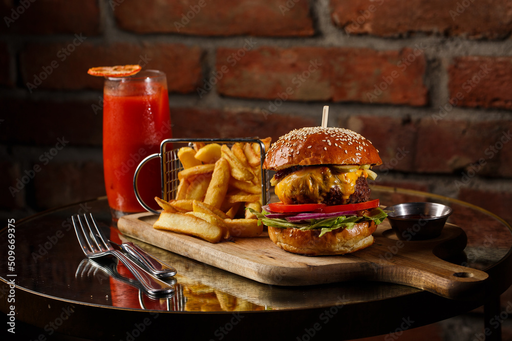 Big cheeseburger with french fries isolated on white background. Hamburger with beef patty onion, tomato, lettuce pickles, melted cheddar, mustards, tomato jam, mayo