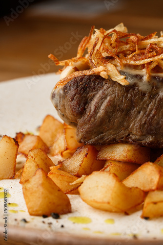 Obraz na płótnie Grilled steak with baked golden potatoes served with crispy onion on top on a brick background. Delicious Recipe. w salonie