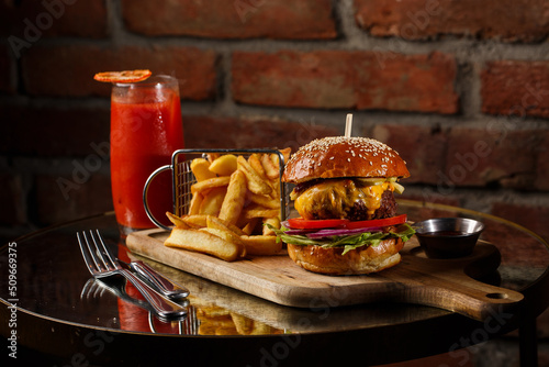 Obraz na płótnie Big cheeseburger with french fries isolated on white background. Hamburger with beef patty onion, tomato, lettuce pickles, melted cheddar, mustards, tomato jam, mayo w salonie