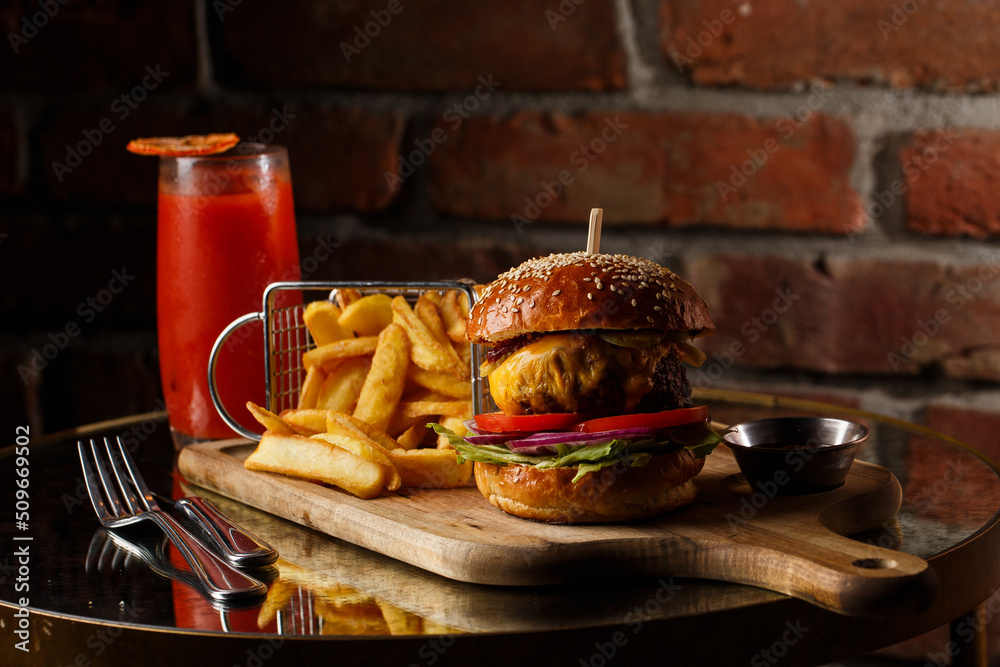 Big cheeseburger with french fries isolated on white background. Hamburger with beef patty onion, tomato, lettuce pickles, melted cheddar, mustards, tomato jam, mayo