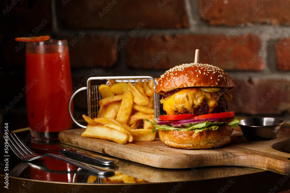 Big cheeseburger with french fries isolated on white background. Hamburger with beef patty onion, tomato, lettuce pickles, melted cheddar, mustards, tomato jam, mayo