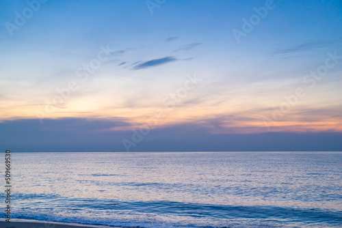 Calm sea with sunset sky and sun through the clouds over. ocean and sky background. Tranquil seascape. Horizon over the water. Sunset sky over sea in the evening with colorful clouds orange sunlight © Ingon