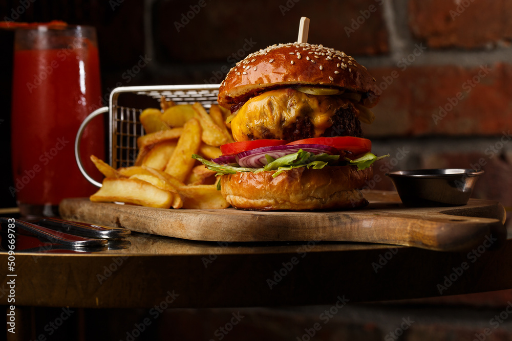 Big cheeseburger with french fries isolated on white background. Hamburger with beef patty onion, tomato, lettuce pickles, melted cheddar, mustards, tomato jam, mayo