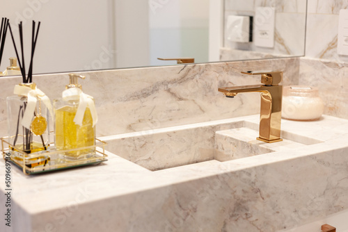 Luxurious bathroom decorated with marble stones. Bronze faucet detail.