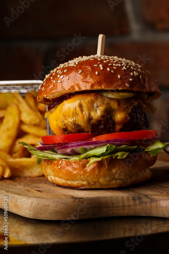 Obraz na płótnie Big cheeseburger with french fries isolated on white background. Hamburger with beef patty onion, tomato, lettuce pickles, melted cheddar, mustards, tomato jam, mayo w salonie