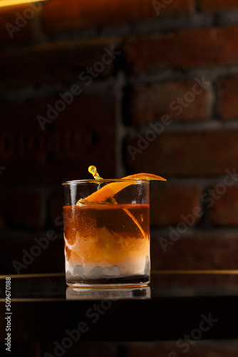 Obraz na płótnie Crystal glass with bright cold alcoholic cocktail decorated with orange zest. Blurred background. Negroni cocktail. w salonie