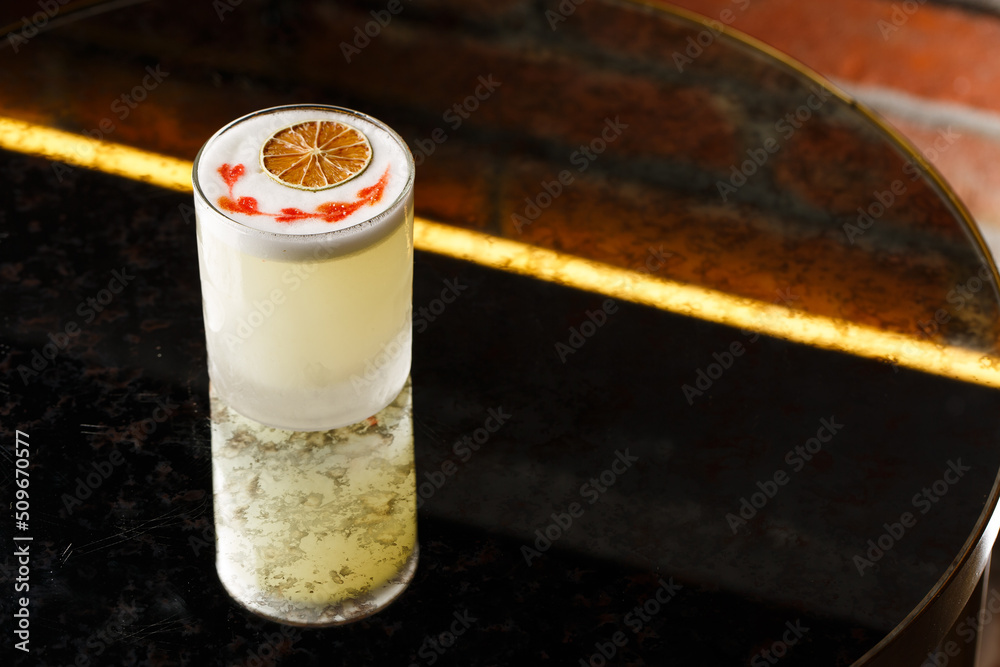 Pisco sour cocktail - whiskey with lime, egg white, sugar syrup in glass on dark background. Space for text