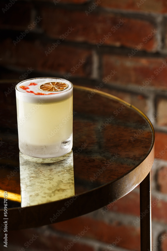 Pisco sour cocktail - whiskey with lime, egg white, sugar syrup in glass on dark background. Space for text