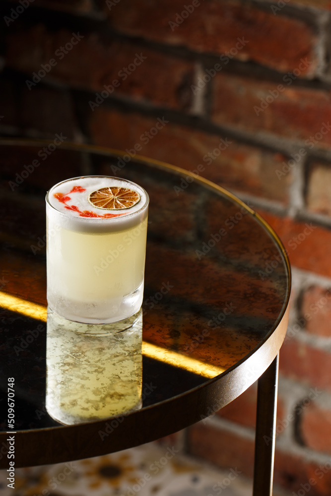 Pisco sour cocktail - whiskey with lime, egg white, sugar syrup in glass on dark background. Space for text