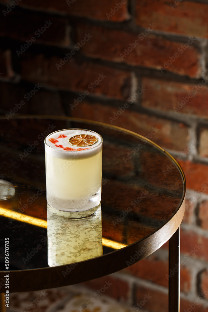Pisco sour cocktail - whiskey with lime, egg white, sugar syrup in glass on dark background. Space for text