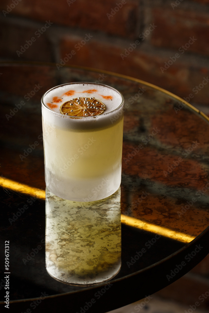 Pisco sour cocktail - whiskey with lime, egg white, sugar syrup in glass on dark background. Space for text