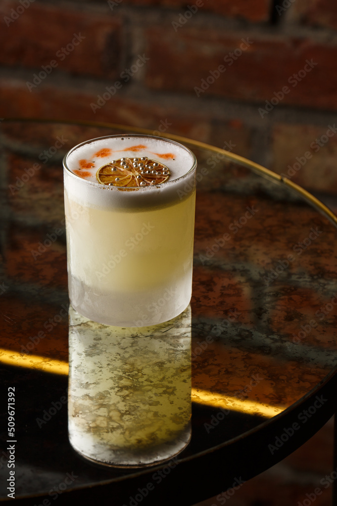 Pisco sour cocktail - whiskey with lime, egg white, sugar syrup in glass on dark background. Space for text