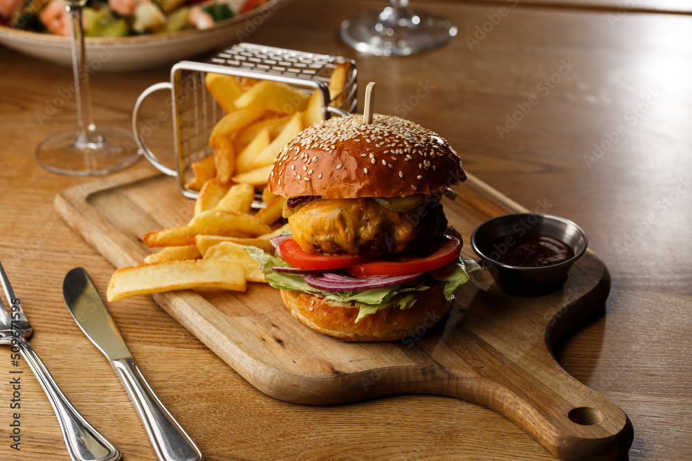 Big cheeseburger with french fries isolated on white background. Hamburger with beef patty onion, tomato, lettuce pickles, melted cheddar, mustards, tomato jam, mayo