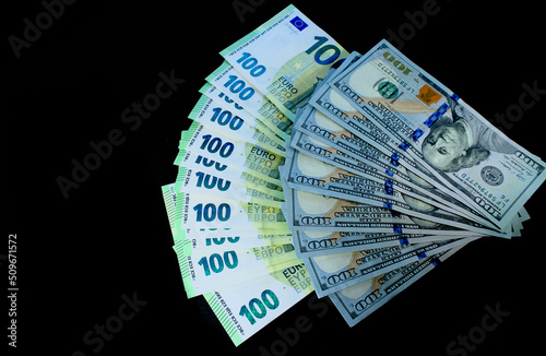 One hundred dollars and euro bills in large quantities fanned out on a black background
