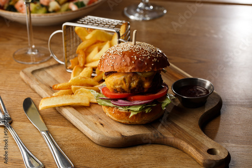 Obraz na płótnie Big cheeseburger with french fries isolated on white background. Hamburger with beef patty onion, tomato, lettuce pickles, melted cheddar, mustards, tomato jam, mayo w salonie