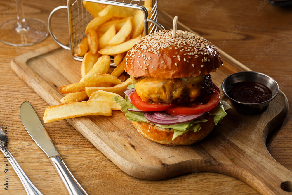 Big cheeseburger with french fries isolated on white background. Hamburger with beef patty onion, tomato, lettuce pickles, melted cheddar, mustards, tomato jam, mayo