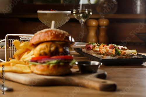 Obraz na płótnie Big cheeseburger with french fries isolated on white background. Hamburger with beef patty onion, tomato, lettuce pickles, melted cheddar, mustards, tomato jam, mayo w salonie