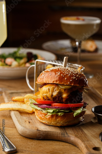 Obraz na płótnie Big cheeseburger with french fries isolated on white background. Hamburger with beef patty onion, tomato, lettuce pickles, melted cheddar, mustards, tomato jam, mayo w salonie