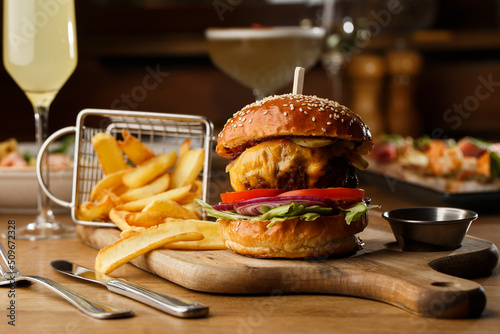 Obraz na płótnie Big cheeseburger with french fries isolated on white background. Hamburger with beef patty onion, tomato, lettuce pickles, melted cheddar, mustards, tomato jam, mayo w salonie