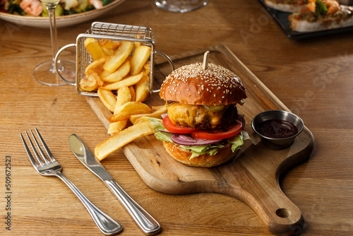 Obraz na płótnie Big cheeseburger with french fries isolated on white background. Hamburger with beef patty onion, tomato, lettuce pickles, melted cheddar, mustards, tomato jam, mayo w salonie