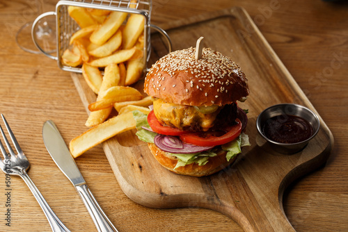 Obraz na płótnie Big cheeseburger with french fries isolated on white background. Hamburger with beef patty onion, tomato, lettuce pickles, melted cheddar, mustards, tomato jam, mayo w salonie