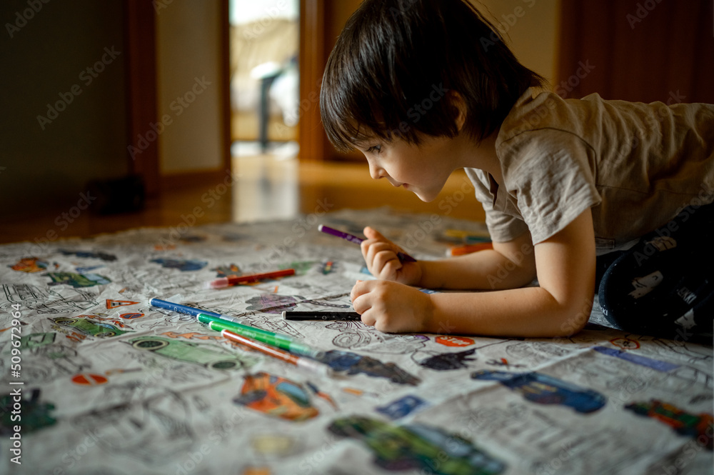 boys draw with colored pencils, a boy of Asian appearance paints a coloring book boys draw with colored pencils, a boy of Asian appearance paints a coloring book