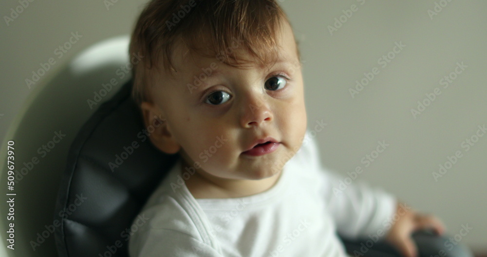 Adorable cute baby pointing to camera smiling. Portrait of infant boy seated on highchair Adorable cute baby pointing to camera smiling. Portrait of infant boy seated on highchair